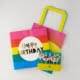 brightly coloured birthday gift package; includes colourful candles, birthday napkins, party poppers and celebration balloons